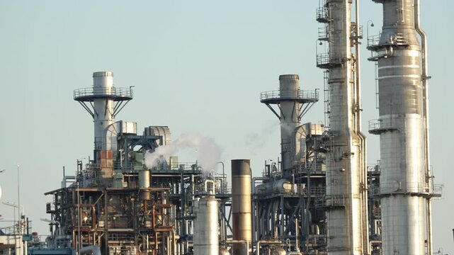 White steam rising from industrial smoke stacks at a large power plant.