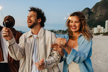 Joyful friends celebrating with sparklers on a beach during a festive evening