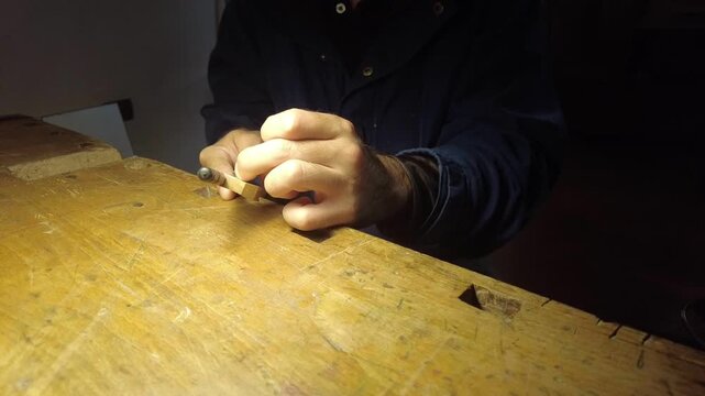 Craftsman meticulously shaping a wooden bow stick for a stringed instrument