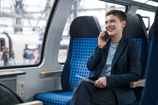 Businesswoman on train making mobile call in wagon compartment