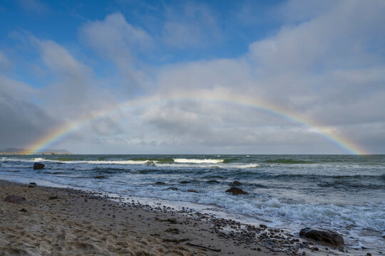 Rainbow over waves at Baltic Sea coast G�hren R�gen island Germany
