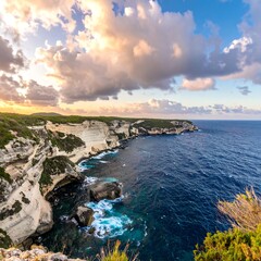 Scenic coastal cliffs meet blue sea under a vibrant sky with colorful clouds, evoking a sense of vastness