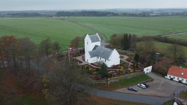 Aerial drone view of a typical Danish village church in Vejlby near Grenaa, surrounded by rural landscape, houses and countryside scenery in Denmark.