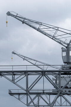 Industrial gantry crane hoist in harbor port steel framework defines infrastructure for cargo logistics under overcast sky with elevated structure