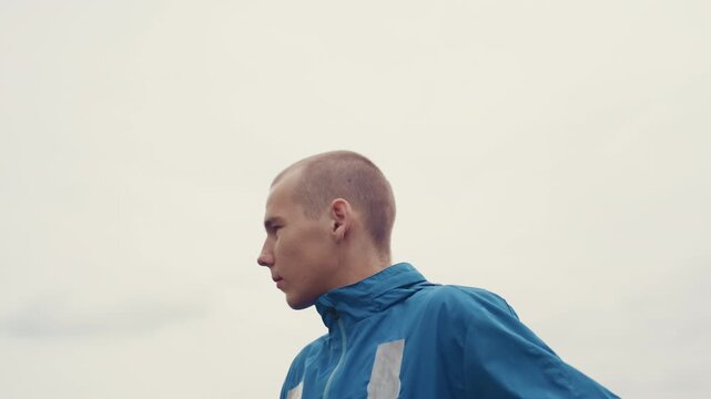 white athlete on city rooftop surveying skyline and preparing for training, profile shots capture calm determination, steady posture, breath control and poised movement against overcast building