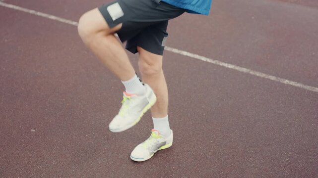 rainy track quickstep warmup and drills, playful lateral shuffles and cadence focus, neon sneakers tapping wet surface, blue windbreaker movement, upbeat energy and technique repetition.