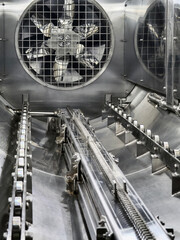 Inside a large metal machine showing a fan and conveyor belt system in operation