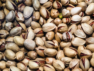 Pistachio nuts in a close-up view showing their shells and kernels on a light background