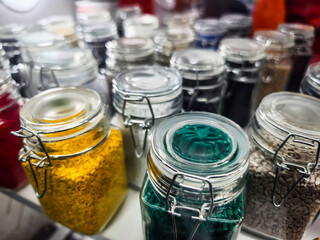 Colorful jars filled with spices and herbs arranged on a shelf in a kitchen