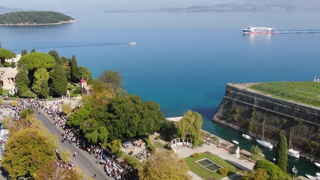 Aerial Drone Pull-Back Reveal of Spianada Square, Corfu Town, During a Parade, with Ferry in Background