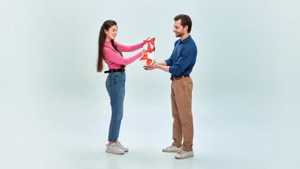 Woman happily receiving wrapped gift from smiling man. Concept of Saint Valentines Day, seasonal...