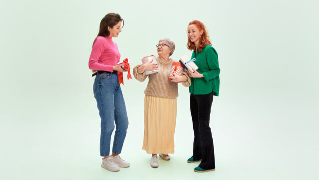 Women of different generations celebrating International Womens Day with gifts. Concept of inclusive holiday advertising, women empowerment marketing, seasonal gift campaigns, warm positive emotion.