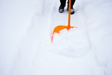 removing a lot of snow by orange plastic shovel after snowfall