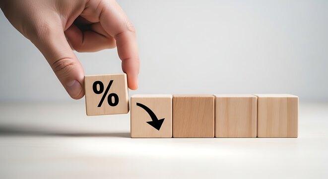 Hand holding a wooden block with a percentage sign and a downward arrow, signifying a decrease in financial metrics or market value.
