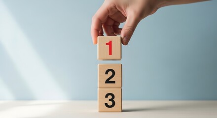Hand placing a '1' block on top of '2' and '3' blocks, representing order, sequence, and simple steps in a process or numbered list.
