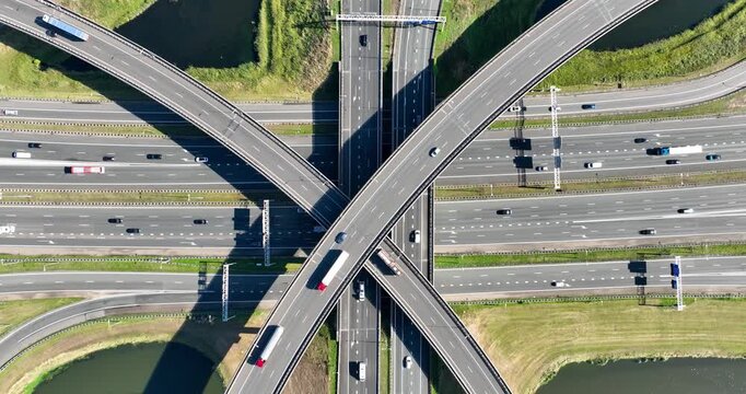 Aerial view of a multilevel highway interchange with busy car traffic. Modern urban infrastructure, road junction, and city transportation system from above. Drone shot of cars.