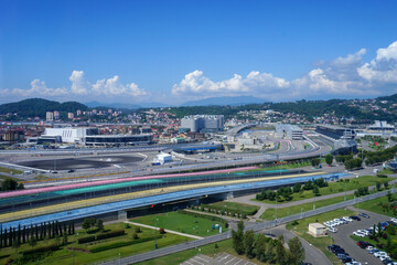 Obraz premium Sochi Autodrom and cityscape with mountains under blue sky