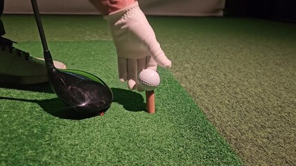 Golf practice at indoor range with driver and tee set up on artificial turf