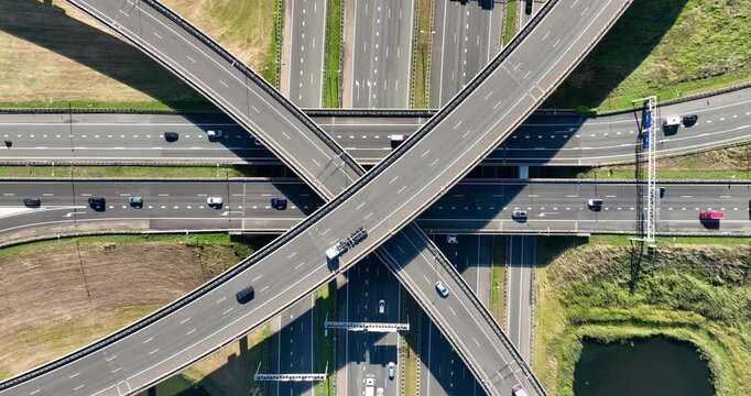 Aerial view of a multilevel highway interchange with busy car traffic. Modern urban infrastructure, road junction, and city transportation system from above. Drone shot of cars.