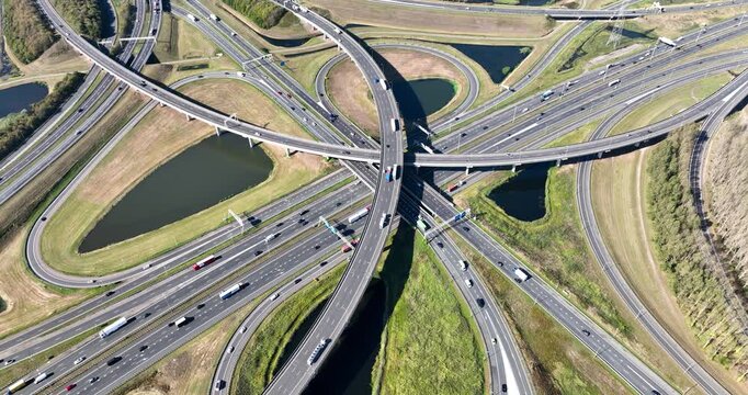 Aerial view of a multilevel highway interchange with busy car traffic. Modern urban infrastructure, road junction, and city transportation system from above. Drone shot of cars.