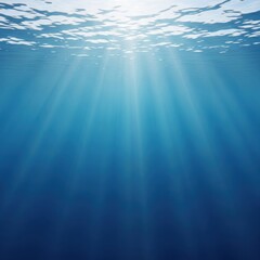 Obraz premium Bright sun rays penetrating deep blue underwater ocean, tranquil marine environment with light effects on clear water surface.