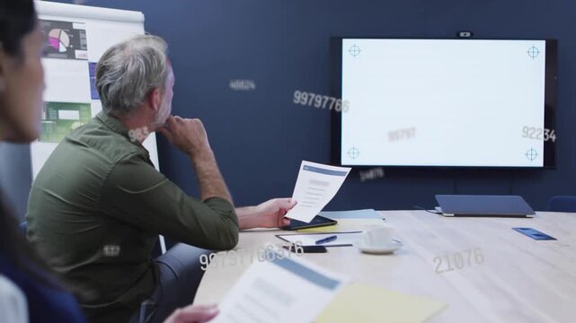 Man reading data sheet and generating flowing numbers over blank screen during business meeting