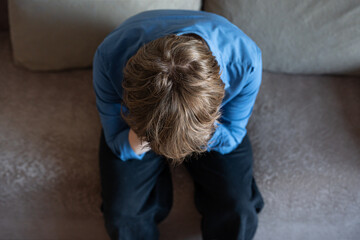 Young man (zoomer) sitting with head down in stress, burnout and mental exhaustion.