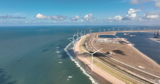 Aerial view of wind turbines on the Maasvlakte beach in the Netherlands. Drone shot of a coastal wind farm near Rotterdam port generating renewable energy. Industrial Holland landscape.