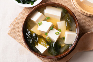 Top view of healthy Japanese miso soup with soft tofu and seaweed in a wooden bowl with spoon