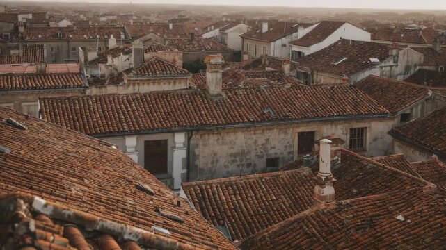 Panning camera revealing terracotta clay roofs in historic urban area, showing chimneys and vents
