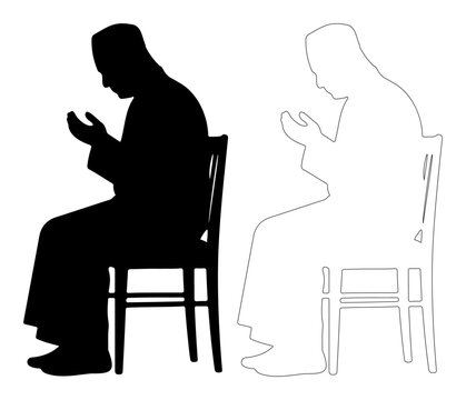 Elderly man praying while sitting on chair