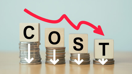 Four stacks of coins with wooden blocks spelling COST and a red arrow indicating a downward trend