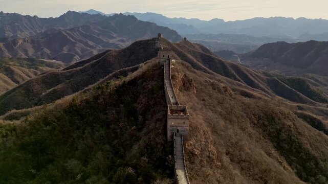 Aerial view of The Great Wall snaking across rugged, mountainous terrain, a stone dragon against the undulating landscape, Huairou District, China.