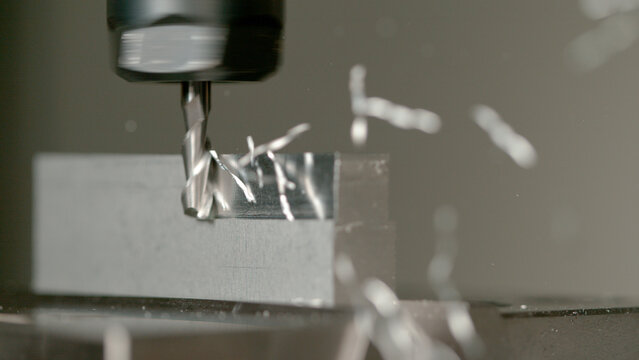 MACRO, DOF: Sharp end mill shaves the side of a small aluminium workpiece.