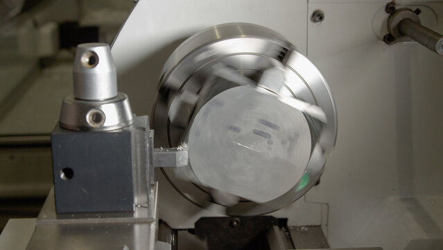 CLOSE UP: Small piece of aluminium is spun by a CNC machine to shave its edges