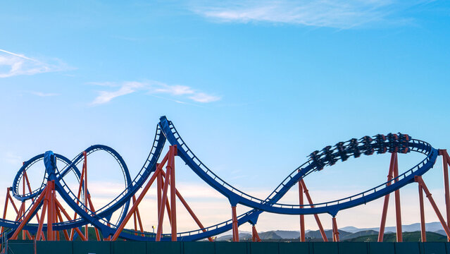 CLOSE UP: Cool shot of a roller coaster driving into a twister on sunny evening.
