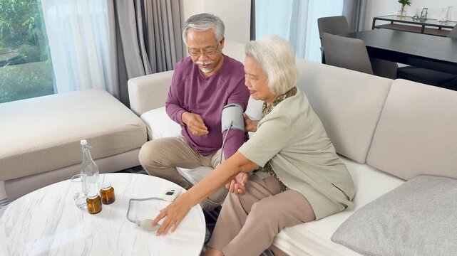 Senior Asian Couple Checking Blood Pressure at Home Together