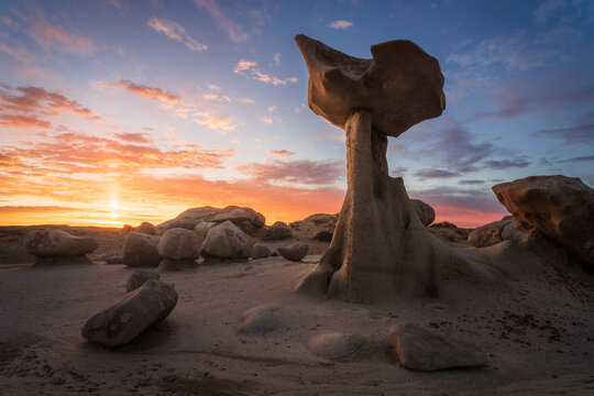 View of a surreal landscape where bizarre rock formations meet a fiery sunset, casting long shadows across the desert floor, Farmington, New Mexico, United States.