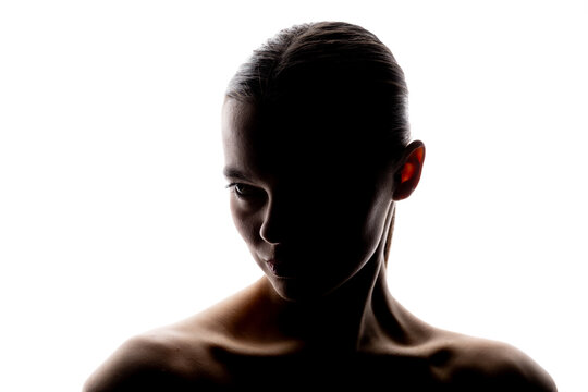 Close-up silhouette of a woman looking sideways with a strong, focused expression. High contrast lighting with visible facial contours and white background. Includes copy space