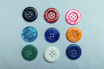 Colorful buttons are seen neatly arranged on a white cloth.