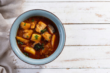Cod with potatoes on white wooden table.Traditional Spanish dish. Top view. Copy space