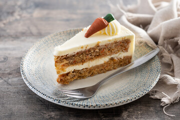 Carrot cake slice with cream cheese frosting on wooden table