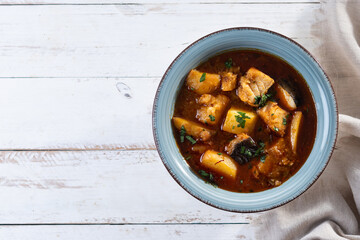 Cod with potatoes on white wooden table.Traditional Spanish dish. Top view. Copy space