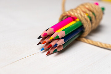colored pencils tied with a string on a white table