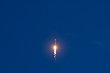 Fototapeta premium Rocket launch against clear blue sky with bright flame trail