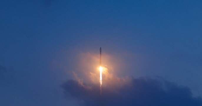 Rocket launch illuminating evening sky with glowing trail, aerospace program concept