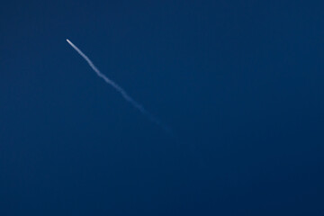 Fototapeta premium Rocket launches into clear blue sky leaving white trail