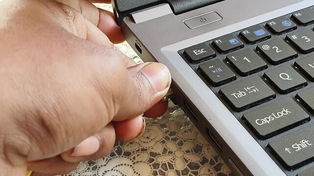 Hand plugging or connecting Ethernet or rj45 internet connector optical fiber cable cord used for lan and wan network connection into a laptop port. Communication, cyberspace and networking concept