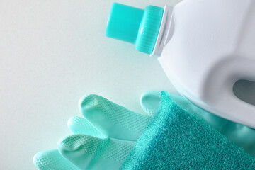 disinfectant with scouring pad and green gloves on white table