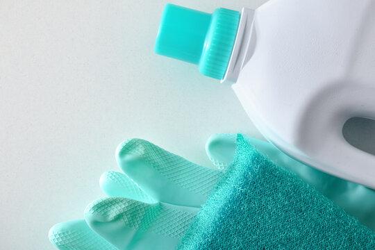 disinfectant with scouring pad and green gloves on white table